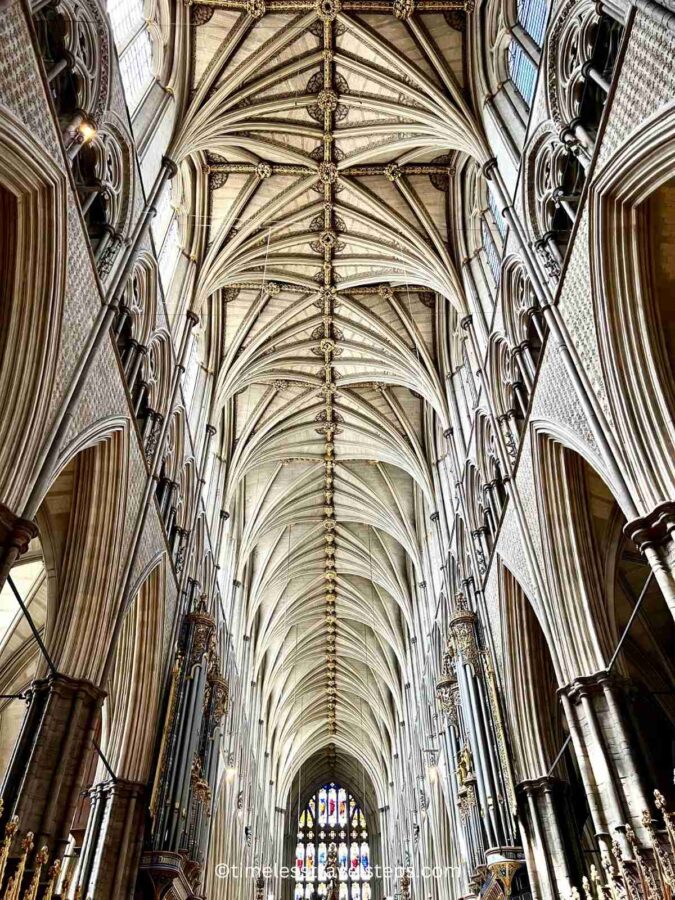 Long view of the nave at Westminster Abbey from the north, extending all the way to the quire. The image captures the soaring vaulted ceilings, intricate Gothic architecture, and the grandeur of the central aisle leading to the quire.
