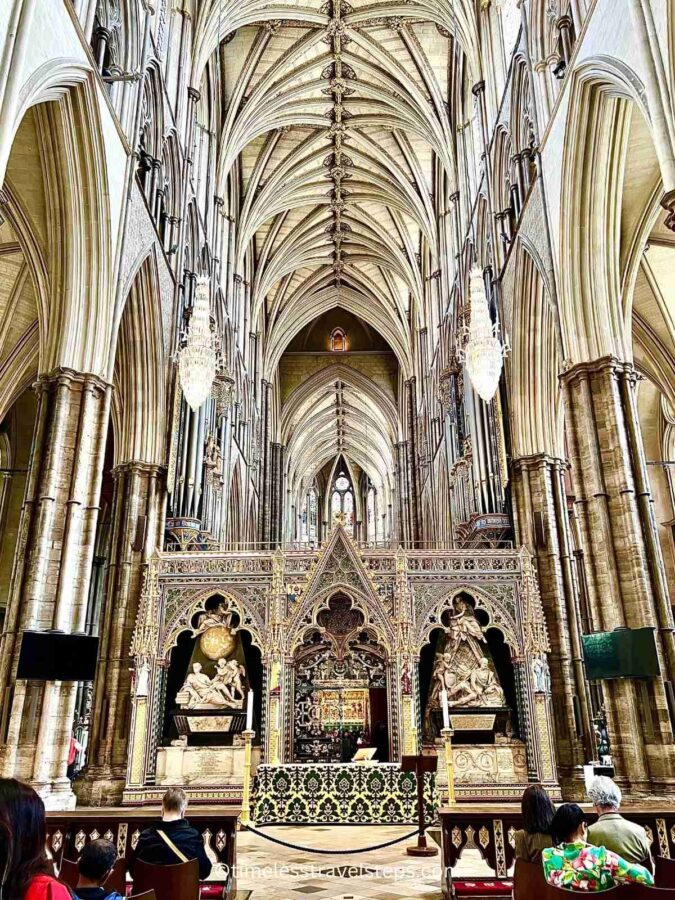 Image of the screen at Westminster Abbey with a partial view of the vaulted ceiling above, highlighting the intricate Gothic design and detailed stonework.
