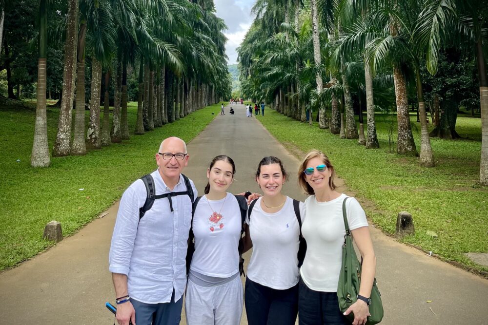 Travelers on Peradeniya Botanical Garden's Avenue of Royal Palms, Sri Lanka.