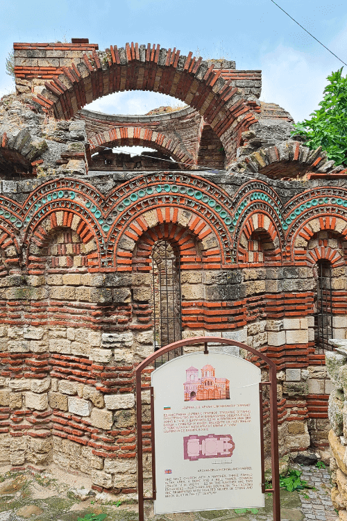 Red and white brick and green glass adorn the arches the decorate the exterior of Archangels Michael and Gabriel Church in Nessebar Bulgaria.