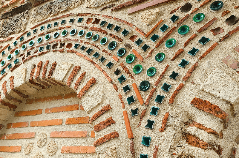 A close up look at the layers of stone, brick, concrete, and decorative glass that pattern the side of the ancient church of Saint Paraskeva in old town Nessebar Bulgaria.