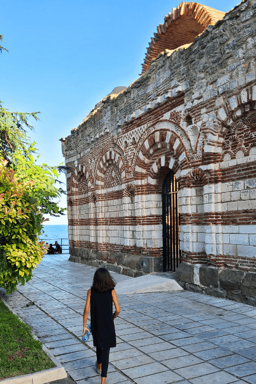 The white and red layered ancient brick of St John Alitourgetos Church at the edge of Nessebar, overlooking the sea.