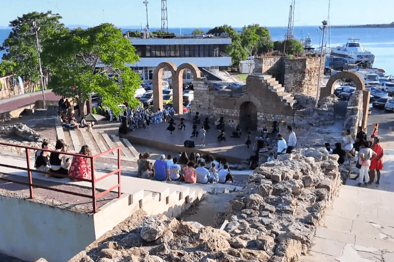 The ancient theater in Nessebar in front of the sea. Children dressed in black as soldiers prepare for a performance.