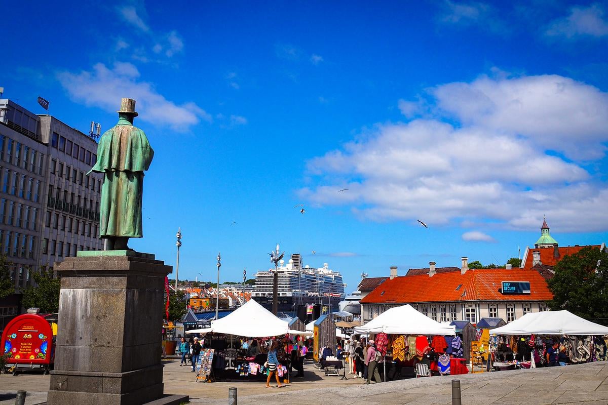 Stavanger market stalls vibrant under blue skies with historic statue in Norway