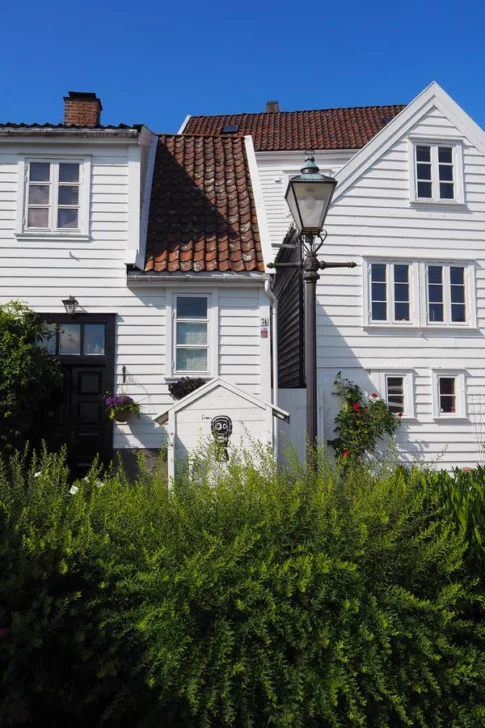 Historic white wooden homes in Gamle Stavanger, Norway, surrounded by lush greenery and traditional architecture