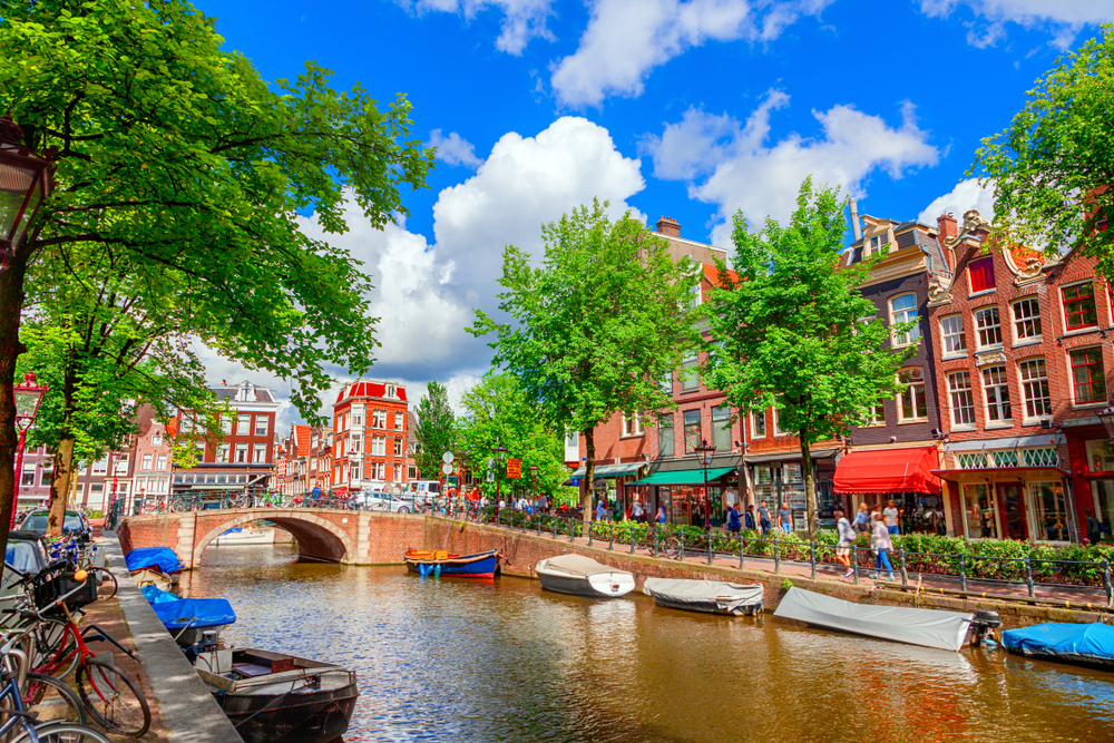 Canal in Amsterdam surrounded by bikes and colored buildings.