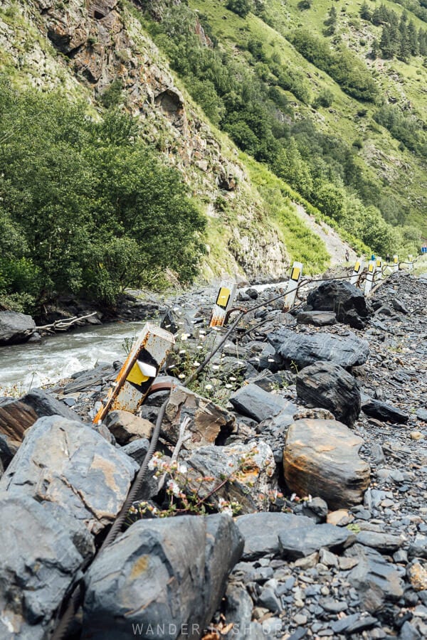 Metal safety rails fall into the river alongside a road near Shatili.