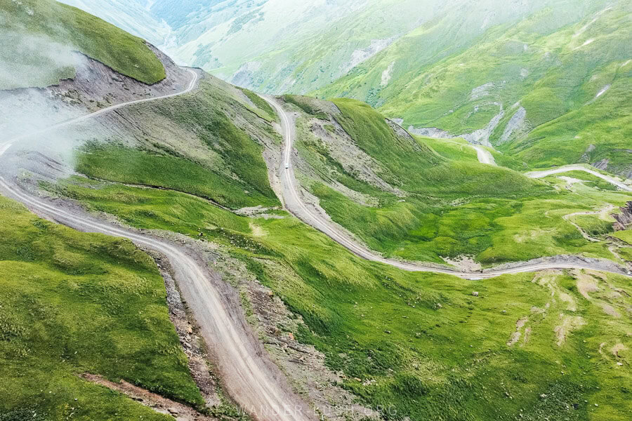 An aerial shot of a car driving on the Datvisjvari Pass in remote Georgia.