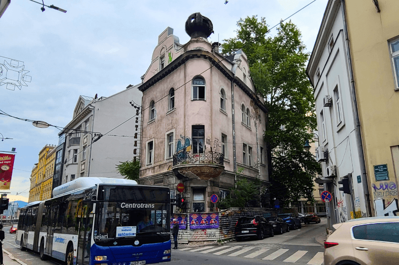 A blue city bus drives by on a street in downtown Sarajevo.