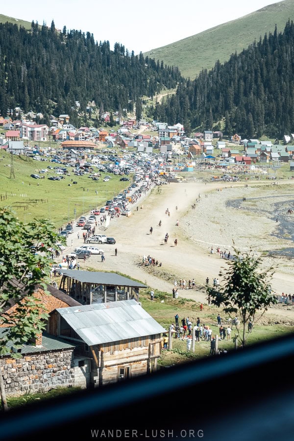 Racers move along a dirt track in Bakhmaro, with a crowd gathered to watch.