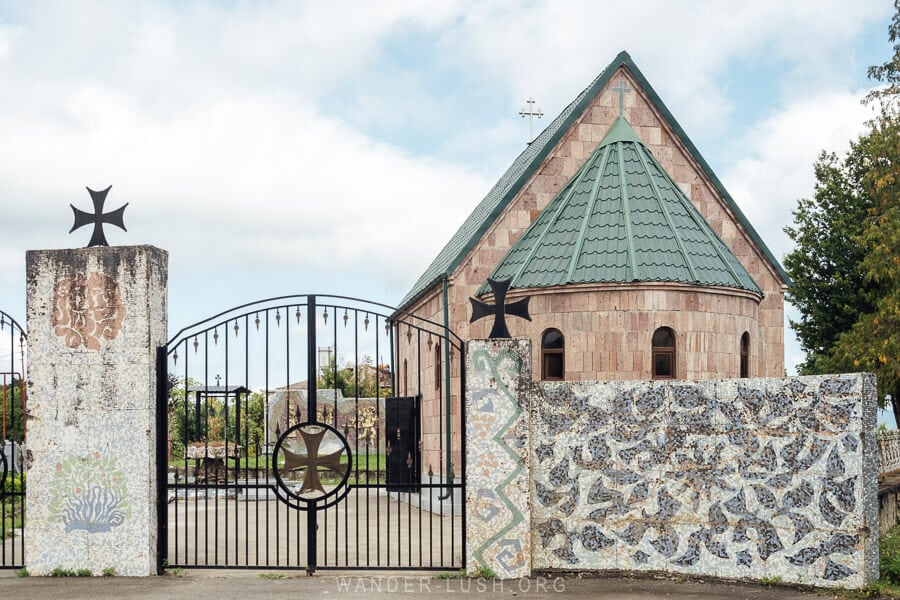 A low wall clad in mosaics in front of a new church in the village of Chaisubani, Georgia.