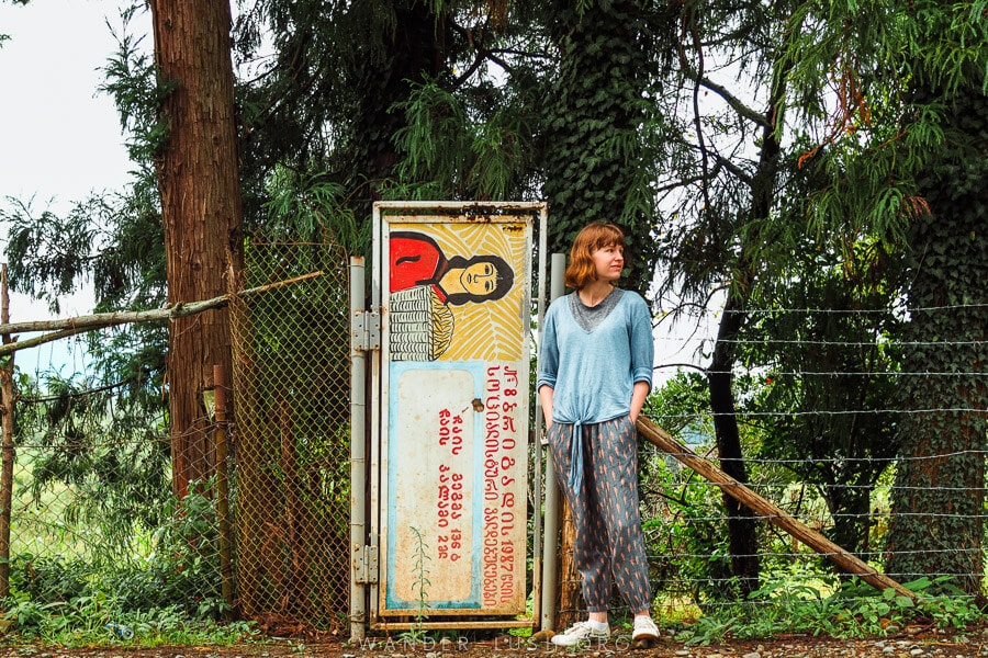 A woman stands in front of a gate made from an old Soviet sign.