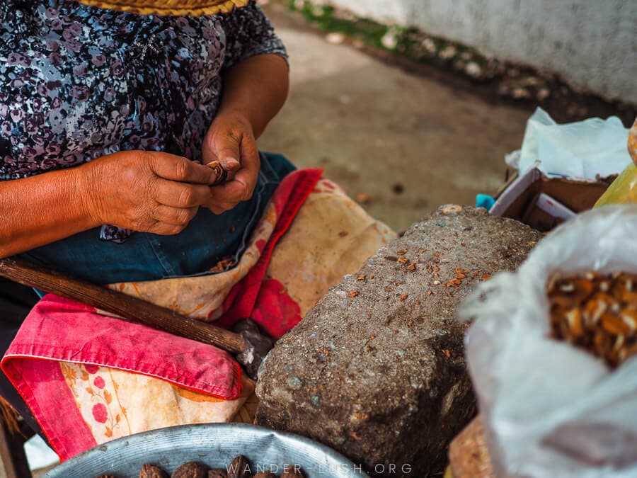 A woman uses a hammer and stone to crack hazelnuts at the market in Ozurgeti.