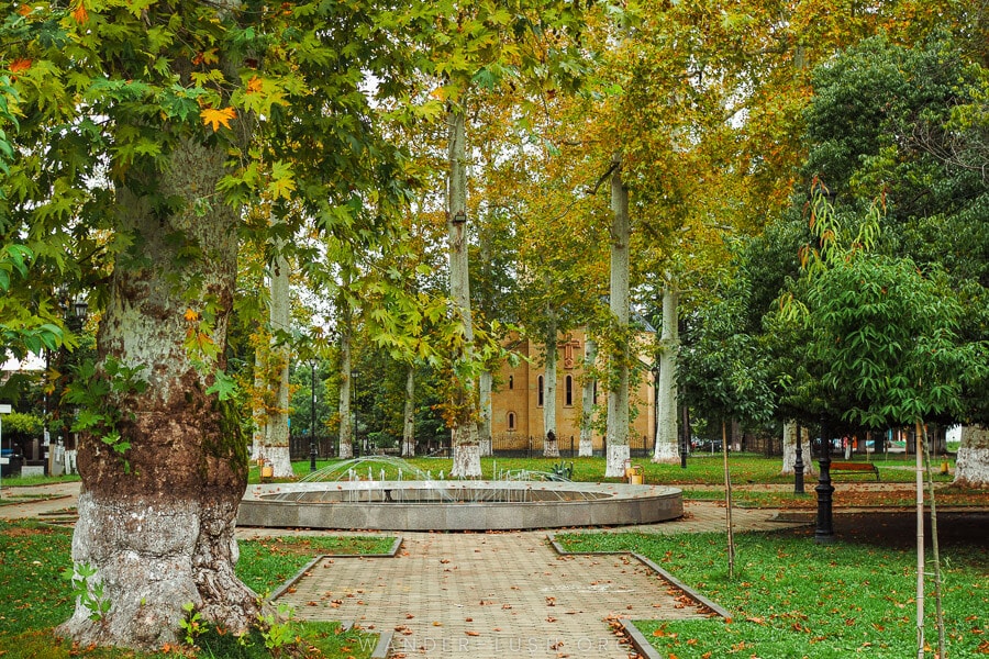 A leafy public garden with a fountain in the city of Ozurgeti.