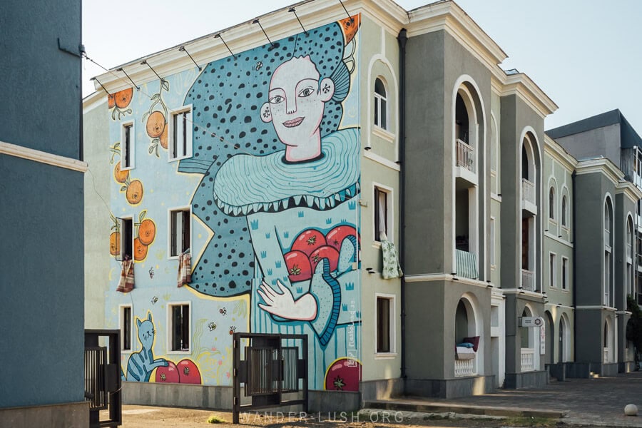 Masholand mural in Ozurgeti, Georgia depicting a woman clutching tomatoes on the side of a building.