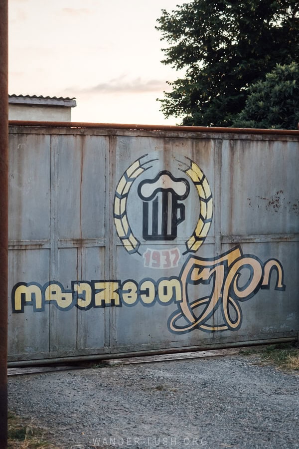 The gate of a brewery in Ozurgeti, Guria painted with a glass of beer and a logo.