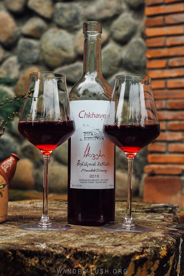 A bottle of Chkhaveri Gurian red wine on a table made from a tree trunk at a vineyard in Ozurgeti.