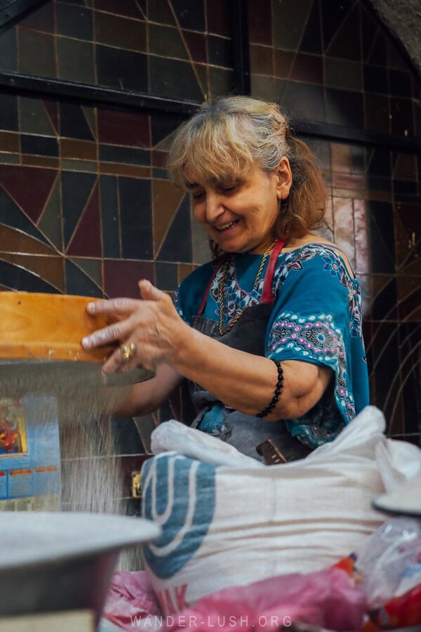 A woman sifting cornflour at the Dezerter Bazaar in Tbilisi.