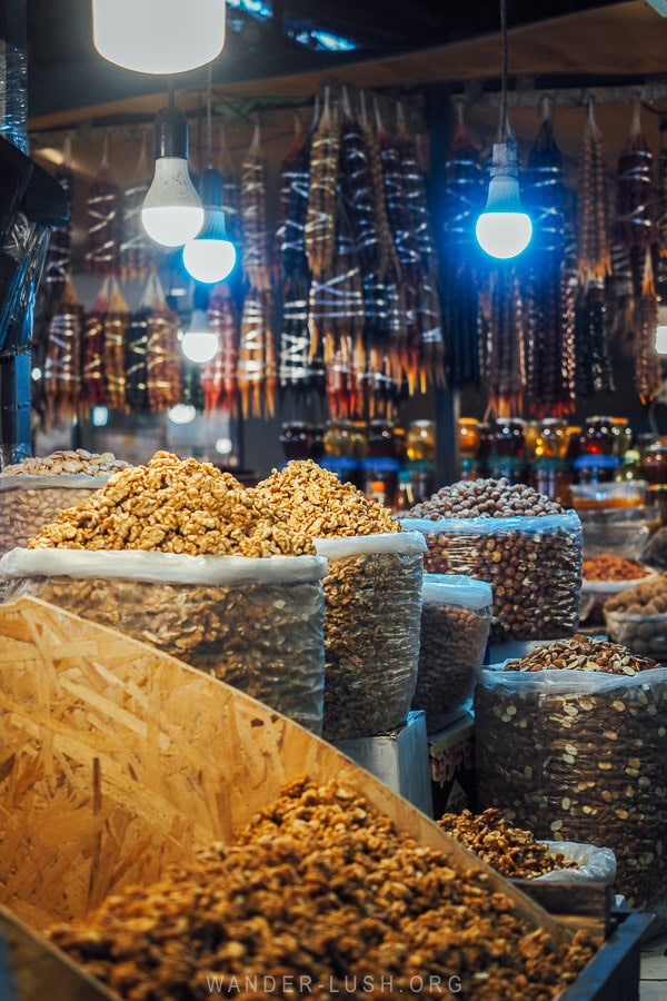 Piles of walnuts and churchkhela inside a stall under bare lightbulbs at the Dezerter Bazaar in Tbilisi.