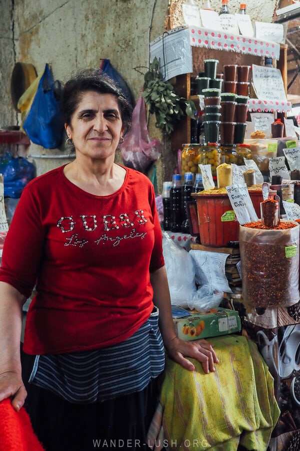 A woman named Nino smiling for a photo in front of her spice stall at the Desertir Market in Tbilisi.