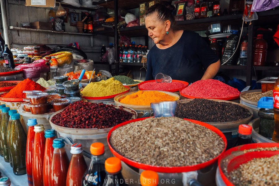 A woman named Luiza stands behind piles of colourful spices, nuts and dried berries at her shop at the Dezerter Bazaar in Tbilisi.