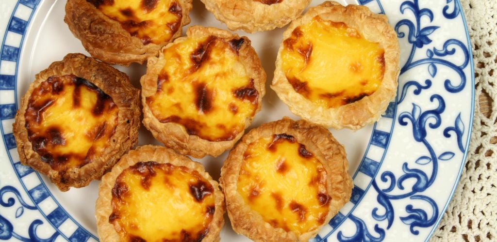 Close up of Portugese custard pastries on a patterned china plate. 