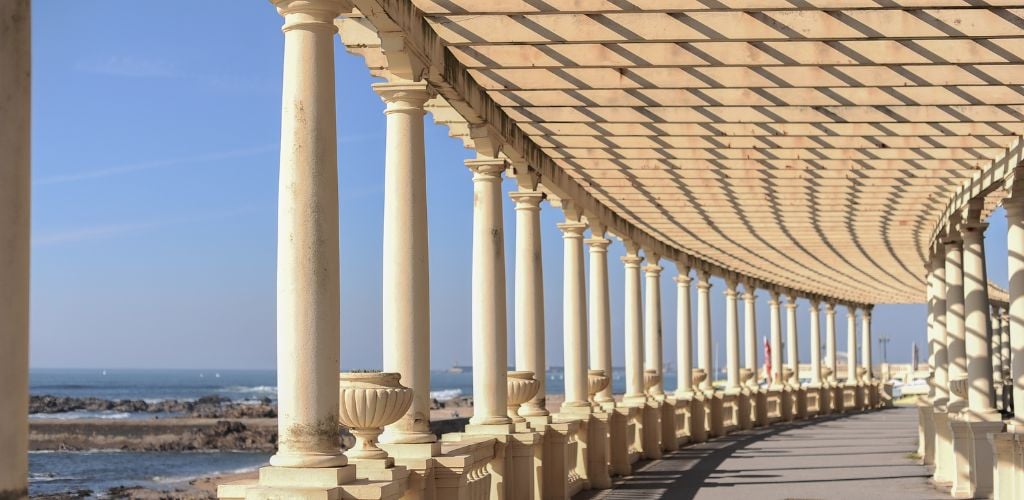 Coastal way with Pergola at Foz do Douro in Portugal, Atlantic Ocean visible through stone columns of pergola 