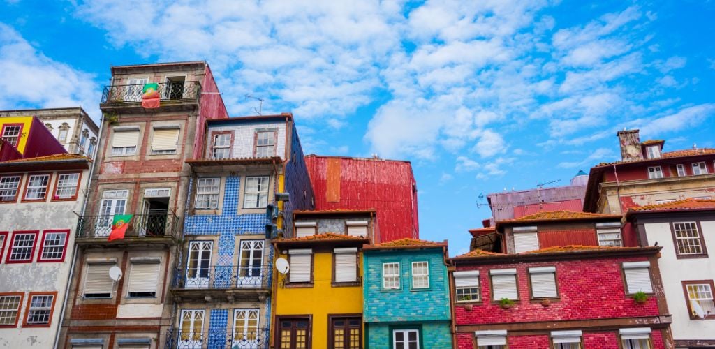 View of the colourful houses of Ribeira, Porto Portugal against a blue sky.