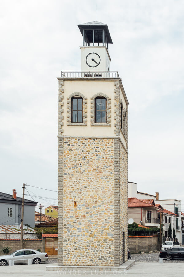 The Clock Tower of Korca, an old stone tower with a clockface on the top.