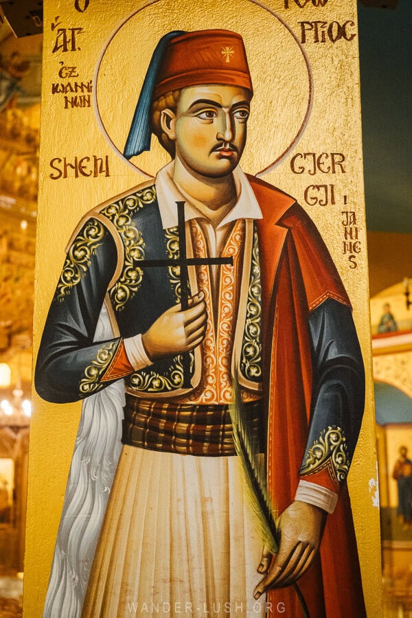 Details of an icon inside the church in Korca, a man dressed in a cap holding a cross.