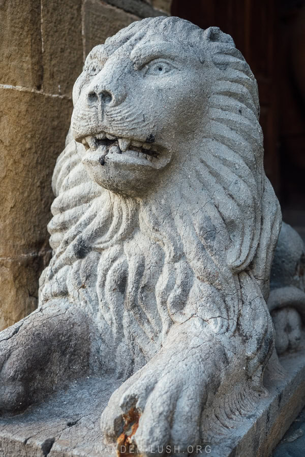 A grey lion sculpture in front of a house in Albania.