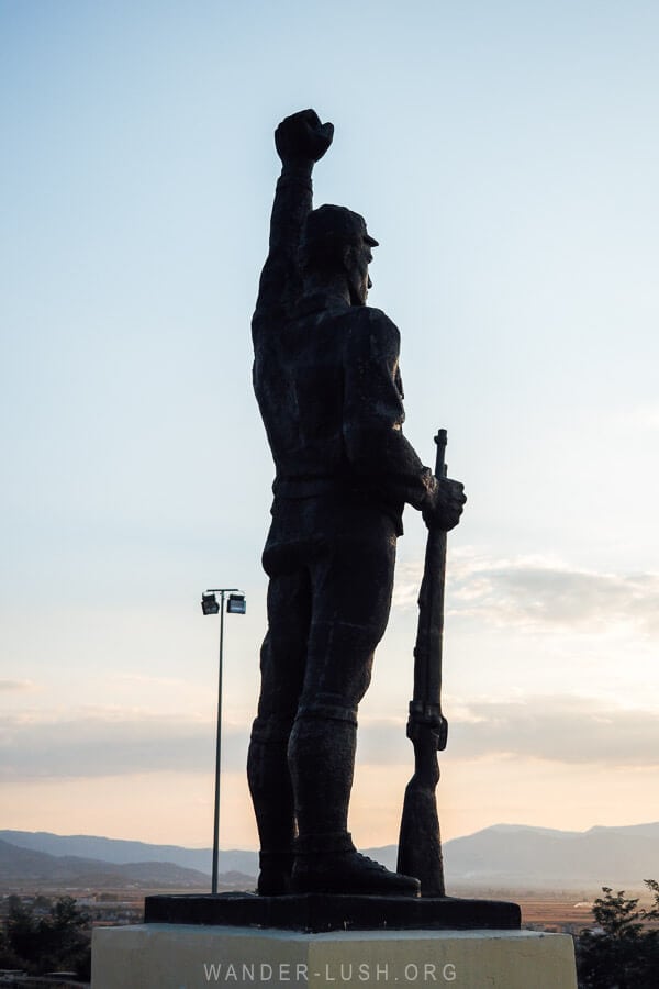 A monument of a partisan fighter with his fist raised to the sky at the Martyrs' Cemetery in Korca, Albania.