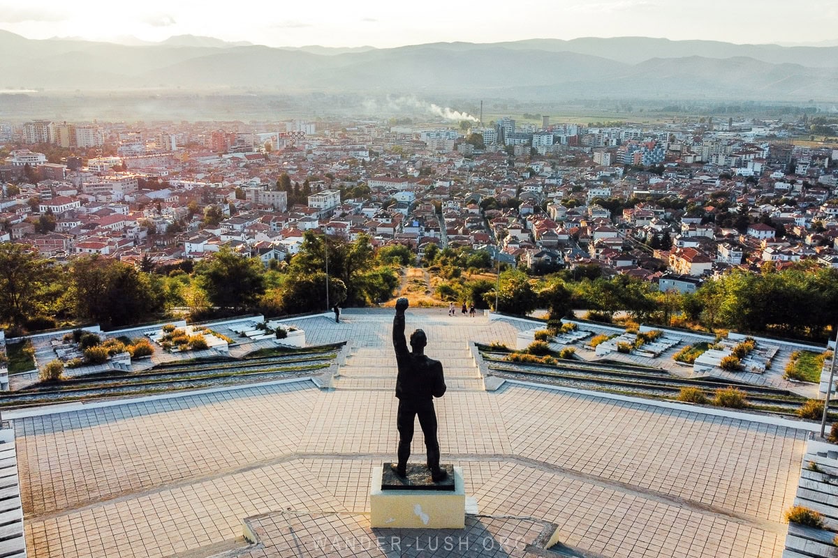 View from the Martyrs Cemetery in Korca, a city scape at dusk with mountains in the background.