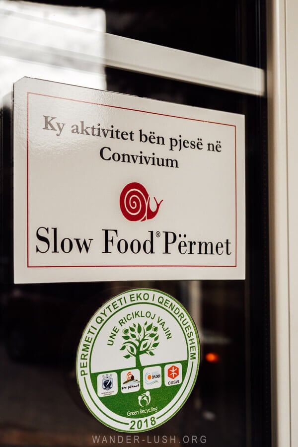 A Slow Food Permet sign in a restaurant window in Permet.