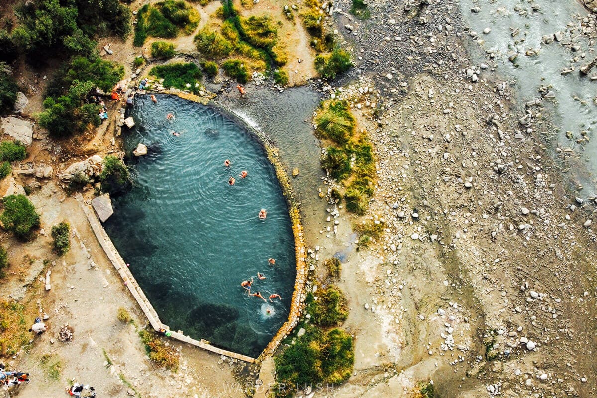 Aerial view of a tear-shaped swimming pool on the edge of a river at the Benja Thermal Baths near Permet.