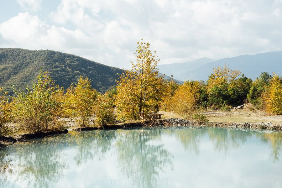 A clear water mineral pool surrounded by autumn foliage in southern Albania.