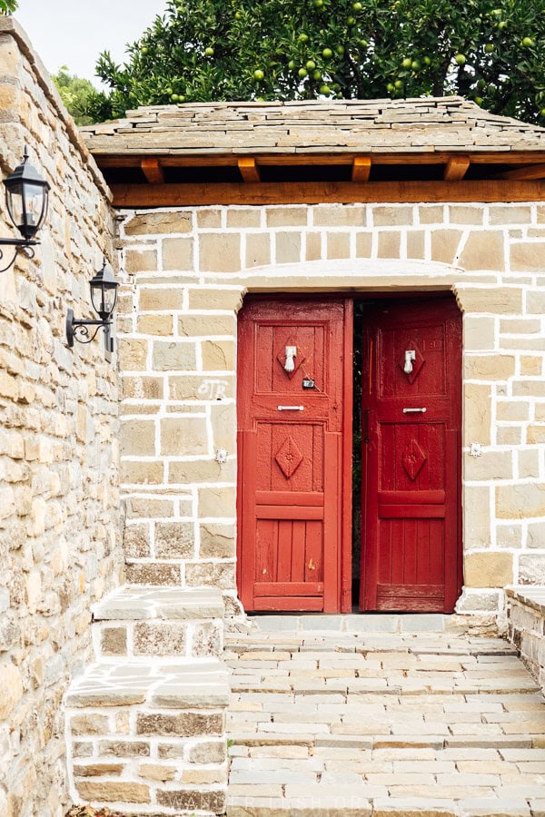 A heritage building in Permet with a red painted door.