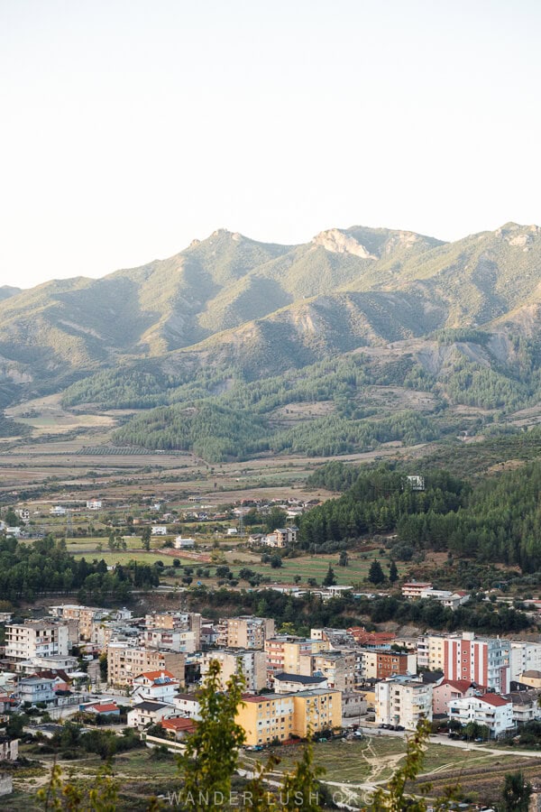 View of colourful apartment blocks in Permet city with a backdrop of mountains.