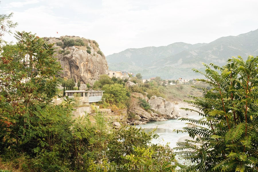 Guri i Qytetit, Permet's city stone visible through the trees on the edge of the Vjosa River.