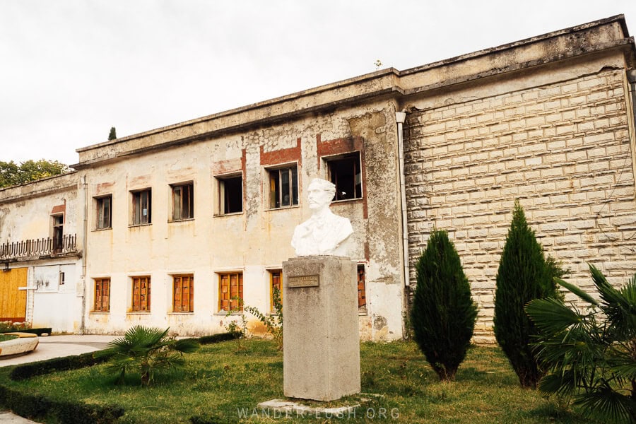 An old building and a bust statue on the main street of Permet.