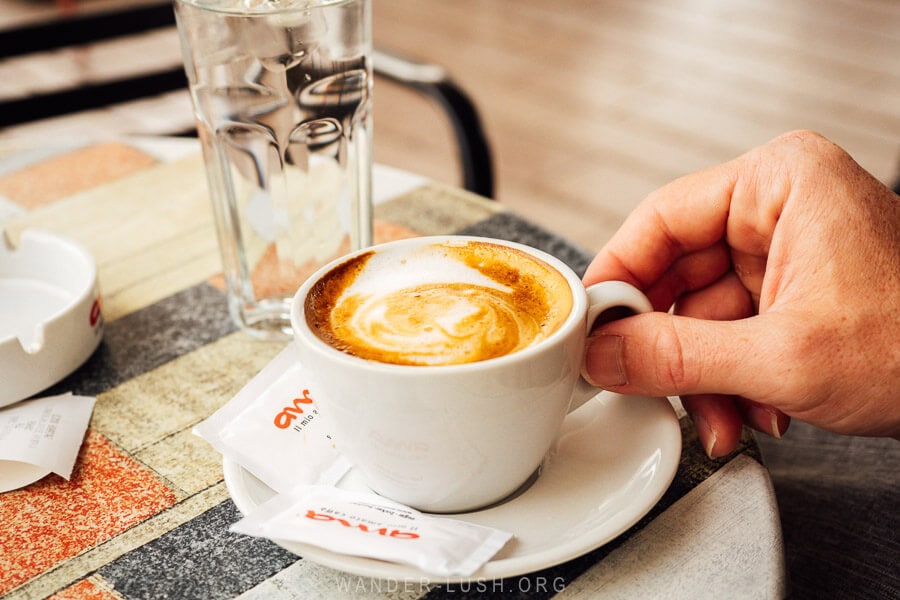 A man holds a small coffee cup at a cafe in Permet, Albania.