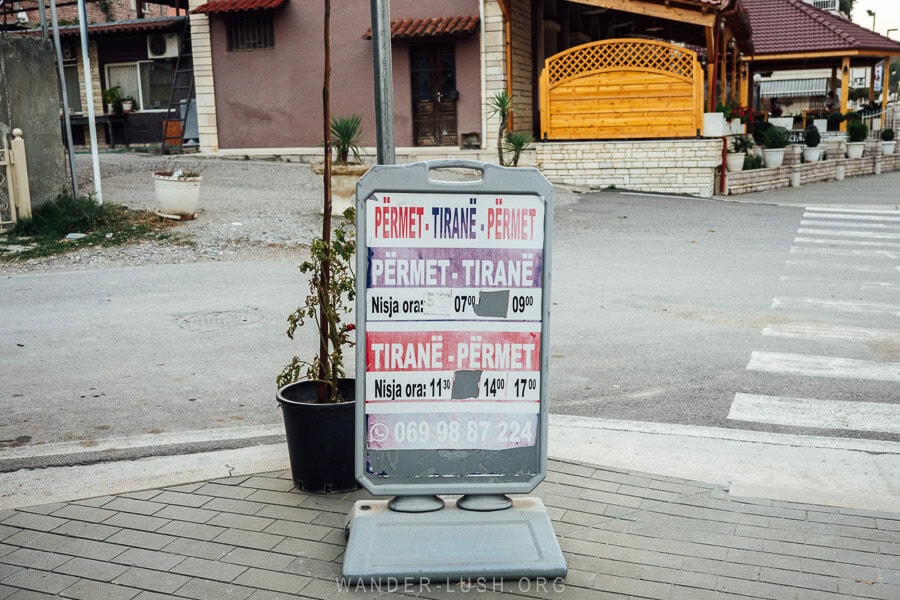 A sign at Permet bus station with travel times to Tirana.