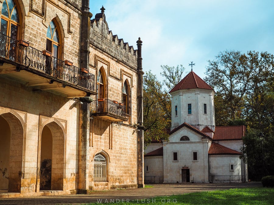 The side of Dadiani Palace in Zugdidi with a small white church in the background.