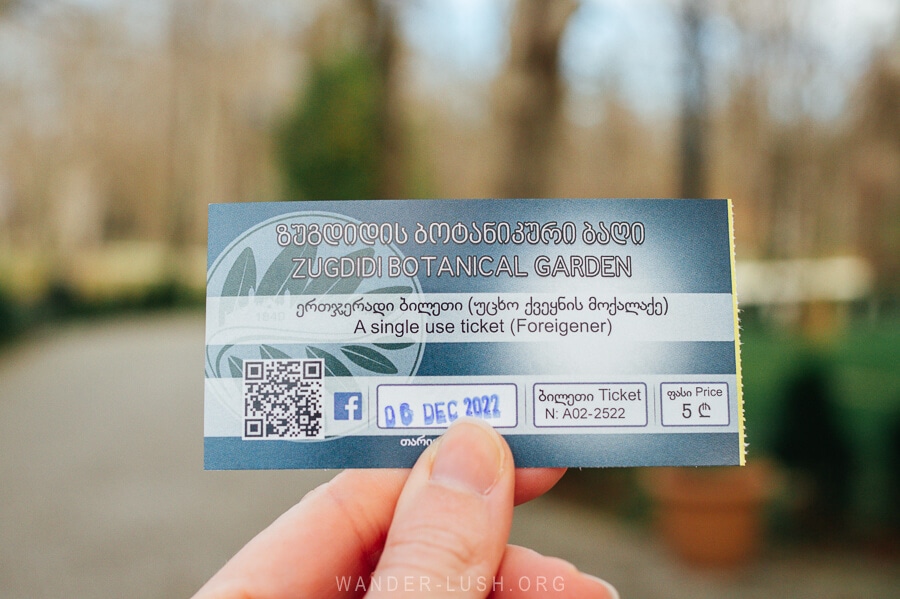 A hand holding up a ticket for the Zugdidi Botanical Garden.