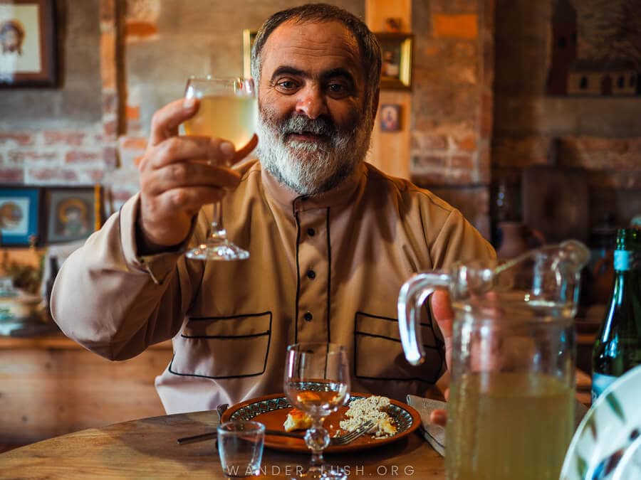 A man raises a glass of wine to toast to a meal at Folk House in Zugdidi.