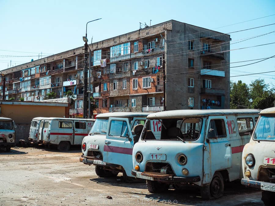 Old Soviet ambulances parked in front of a large apartment block in Zugdidi.