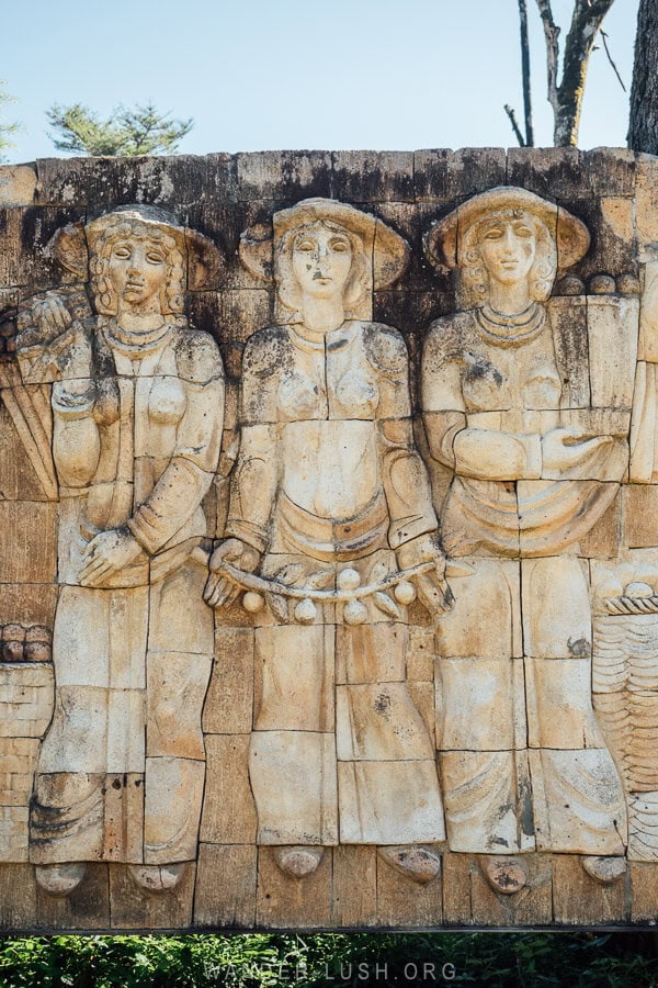 Three tea pickers depicted in a stone relief sculpture at a former collective farm in Samegrelo, Georgia.