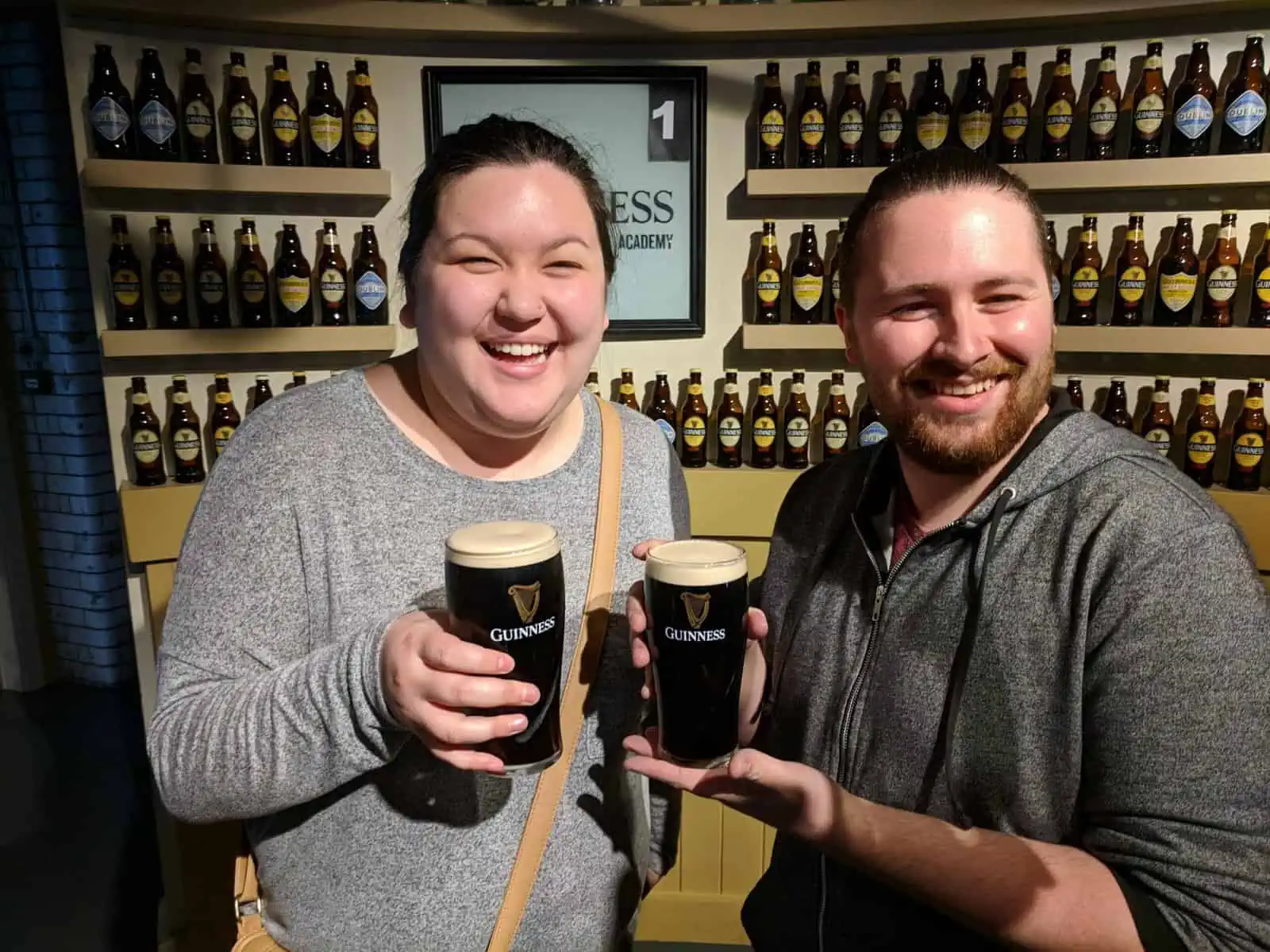 Riana and Colin holding pints of Guinness they just poured at the Guinness Storehouse in Dublin, Ireland