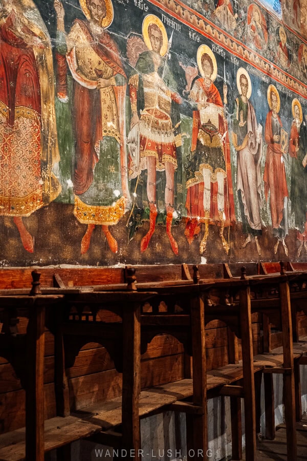 Frescoes and wooden pews inside St Mary's Church of Leus.