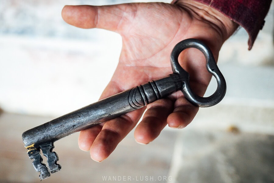 A man holds a heavy antique looking key in his hand, the key to the Church of Leus.